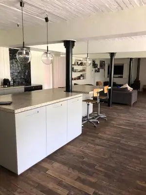 a kitchen with white cabinets and a living room at Vakantiehuis De Sneppelhoeve in Loenhout