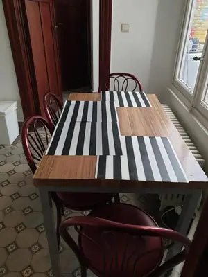 a wooden table with chairs around it with a striped table at Near European District, 1-2 Bedroom Apartment. in Brussels