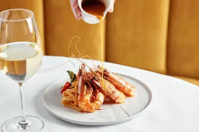 a plate of shrimp and pasta next to a glass of wine at Van der Valk Hotel Gent in Ghent