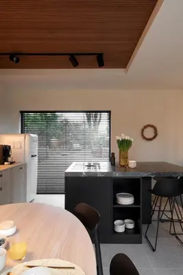 a kitchen with a black island with a sink and chairs at The Pine House B&B in Schoten