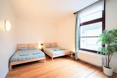 two beds in a room with a large window at The Antwerp Old Town Lodge in Antwerp