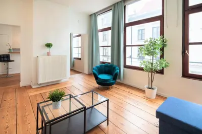 a living room with a blue chair and a table at The Antwerp Old Town Lodge in Antwerp