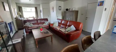 a living room with a leather couch and a table at Vertentenhuis in Hamme