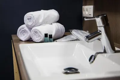 a bathroom sink with towels on top of a counter at Hotel Guzy Lier Centre in Lier