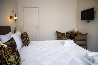 a bedroom with a white bed with a table and a television at Hotel Guzy Lier Centre in Lier