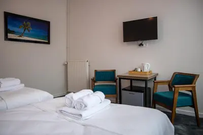 a hotel room with two beds and a desk and a tv at Hotel Guzy Lier Centre in Lier