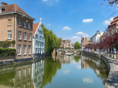a river in a city with buildings and a bridge at Hotel Guzy Lier Centre in Lier
