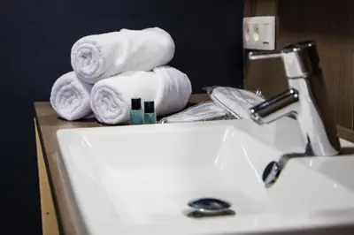 a bathroom sink with towels on top of a counter at Hotel Guzy Lier Centre in Lier