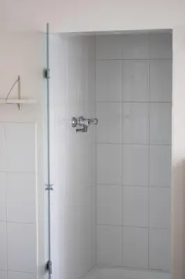 a shower in a bathroom with white tile at B&B Tempelhof in Ghent