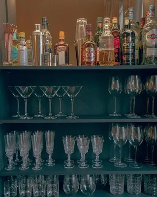 a bunch of wine glasses on shelves with bottles at ADA in Antwerp
