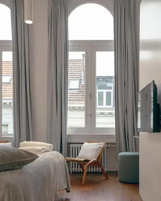 a bedroom with a bed and a chair and a window at ADA in Antwerp