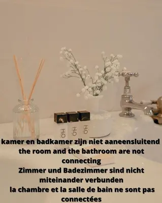 a sign on a bathroom sink with a vase of flowers at ADA in Antwerp