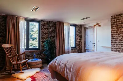 a bedroom with a bed and a chair and windows at Chambre d'Amis by Alix in Ghent