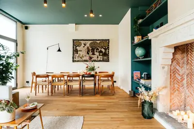 a living room with a dining room table and a fireplace at Chambre d'Amis by Alix in Ghent