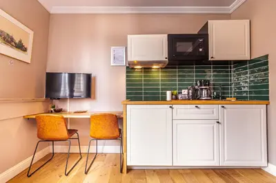 a kitchen with white cabinets and a green tiled wall at Luxury Suites Boutique by Rikas Hotels in Antwerp