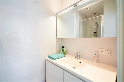 a white bathroom with a sink and a mirror at The Fashion Street Apartments in Antwerp