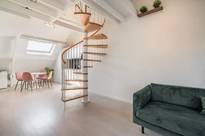 a living room with a green couch and a spiral staircase at The Fashion Street Apartments in Antwerp