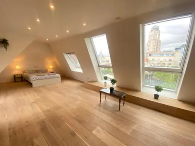 a large room with a bed and two windows at The Central Square Residence in Antwerp
