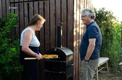 a man and a woman standing next to an oven at Hageland Vakantieverblijf in Holsbeek