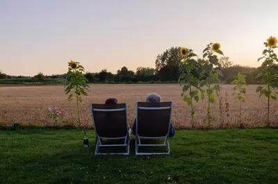 two people sitting in chairs looking out at a field at Hageland Vakantieverblijf in Holsbeek