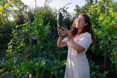 a woman holding a cucumber in a garden at Hageland Vakantieverblijf in Holsbeek