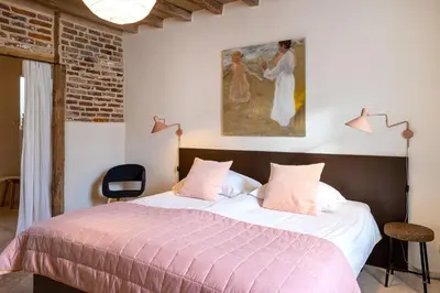 a bedroom with a bed with a painting on the wall at Het Verblijf in Sint-Martens-Lennik