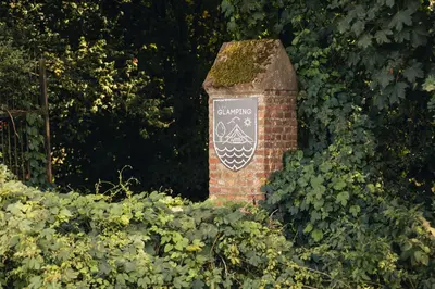 a brick pillar with a sign on it in the bushes at ASILI DELUXE - Zebra in Lichtaart
