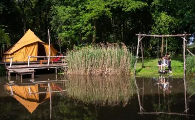 a group of people sitting on a swing by a lake at ASILI DELUXE - Zebra in Lichtaart