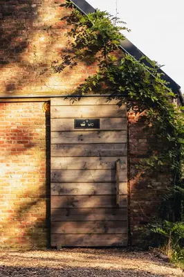 a wooden garage door with ivy on a brick building at ASILI DELUXE - Zebra in Lichtaart