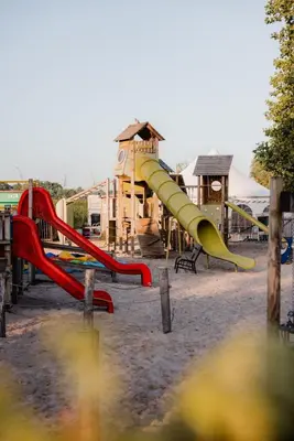 a playground with a slide in front of a building at ASILI DELUXE - Zebra in Lichtaart