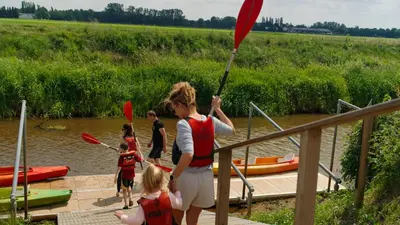 a woman holding a red paddle on a dock at POLE POLE - Ijsbeer in Lichtaart