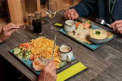 two people sitting at a table with plates of food at POLE POLE - Ijsbeer in Lichtaart