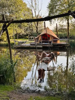 two girls sitting on a swing in a lake at POLE POLE - Ijsbeer in Lichtaart