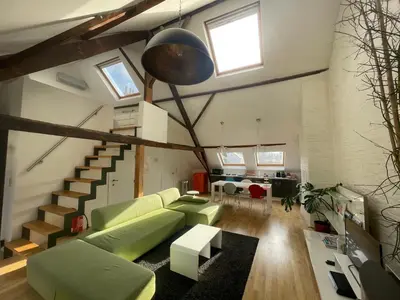 a living room with a green couch and a staircase at Spacious Loft in the Historical Centre in Ghent