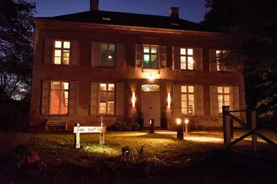 a large house with a sign in front of it at night at B&B Pura Vista in Zandhoven