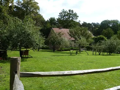 a wooden fence in a field with a house at B&B Zinnen en Minnen in Herselt