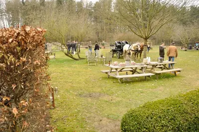 a group of people standing around tables with a horse drawn carriage at B&B Zinnen en Minnen in Herselt