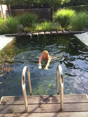 a young girl swimming in a pond at B&B Casa Luna Loft in Dendermonde
