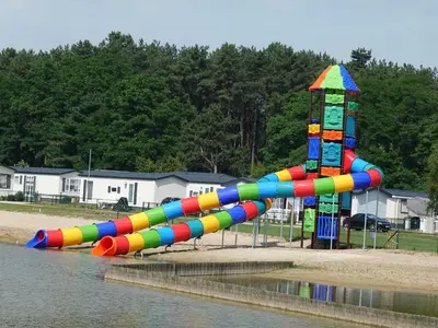 a colorful water slide in a park next to the water at Chalet near Antwerp with Pool Access in Rijkevorsel