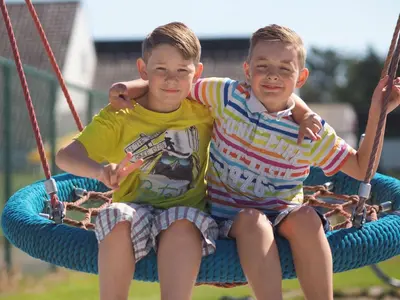 two young boys sitting in a swing at Chalet near Antwerp with Pool Access in Rijkevorsel