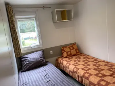 a small bedroom with a bed and a window at Chalet near Antwerp with Pool Access in Rijkevorsel