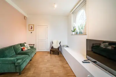 a living room with a green couch and a flat screen tv at La Vista in Tervuren