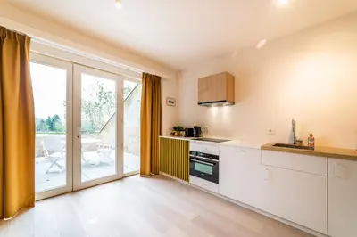 a kitchen with white cabinets and a large window at La Vista in Tervuren