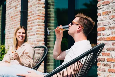 a man and a woman sitting in chairs drinking at Factory Hotel in Beveren