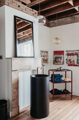 a living room with a black trash can in front of a fireplace at Huis Hector Mechiels ROOM in Sint-Niklaas