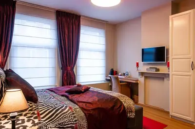 a bedroom with a bed and a desk and a television at Adamas B&B in Dendermonde