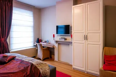 a bedroom with a bed and a desk with a television at Adamas B&B in Dendermonde