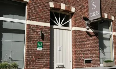 a brick building with a white door and a street sign at Adamas B&B in Dendermonde