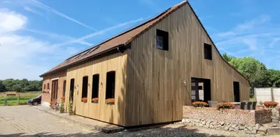 a large wooden barn with windows and a brick wall at B&B D'Hollehoeve in Heist-op-den-Berg