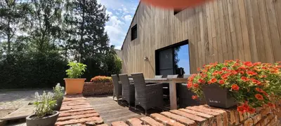 a patio with a table and chairs and flowers at B&B D'Hollehoeve in Heist-op-den-Berg